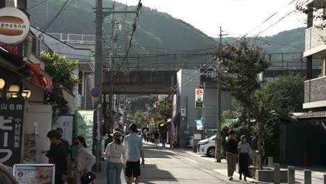 Sonniger-Nachmittagsblick-Auf-Die-Straße,-Die-Zum-Arashiyama-Bambuswald-Führt,-Mit-Menschen,-Die-Entlang-Gehen