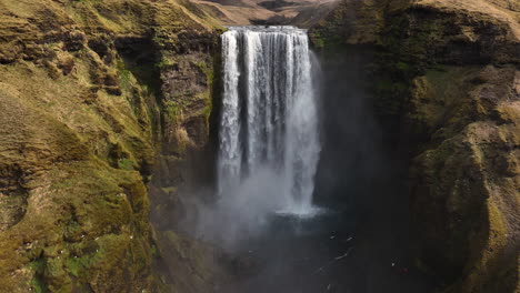 Drone-shot-rotating-toward-the-Skogafoss-waterfall,-sunny-fall-day-in-Iceland