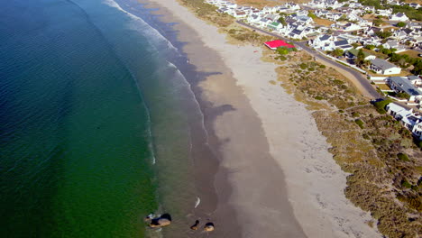 Drone-tilt-up-reveals-scenic-white-houses-of-Paternoster-coastal-town,-Weskus