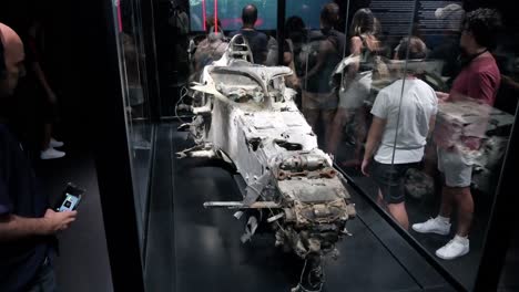 Visitors-look-at-the-remains-of-Romain-Grosjean's-destroyed-car-after-suffering-an-accident-at-the-2020-Bahrain-Grand-Prix-seen-displayed-during-the-world's-first-official-Formula-1-exhibition