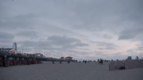 Santa-Monica,-Kalifornien-Strand-Mit-Pier-Und-Meer-Im-Hintergrund-Bei-Sonnenuntergang-In-Zeitlupe