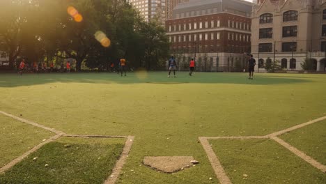 Slow-Motion-pov-dolly-of-soccer-field-with-playing-teenager-during-golden-sunset-with-lens-flare-in-Manhattan-Borough