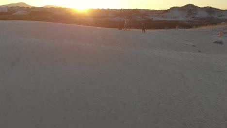 Group-of-tourist-friends-relaxing-on-the-sands-of-beach-Santinho-next-to-greenery-at-golden-hour