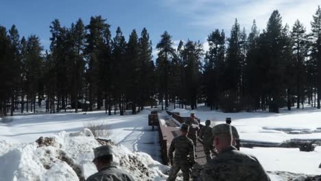 Militares-Caminando-Sobre-Un-Puente-Después-De-Una-Fuerte-Nevada-En-Las-Montañas,-Tiro-De-Mano