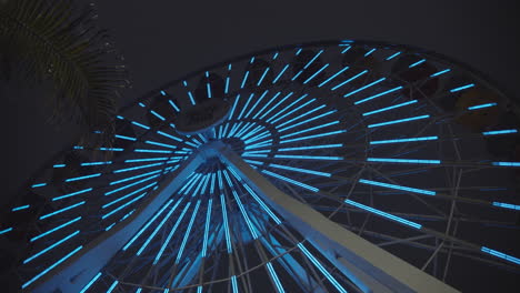 Slow-motion-of-neon-light,-glowing,-ferris-wheel-at-Pacific-Park-Amusement-park-on-the-Santa-Monica-Pier-in-California-at-night