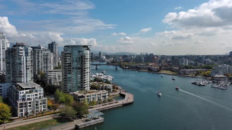 Drone-shot-of-the-Sea-Wall-in-Yaletown-downtown-Vancouver-including-False-Creek,-buildings,-boats,-trees,-bridge-during-summer