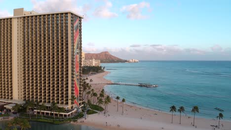 Aerial-Orbit-at-Golden-Hour-of-Kahanamoku-and-Waikiki-Beach,-with-Diamond-Head-Crater-in-the-background