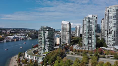 Drone-shot-of-buildings-in-downtown-Vancouver-with-False-creek,-seawall,-buildings,-bridge,-blue-sky