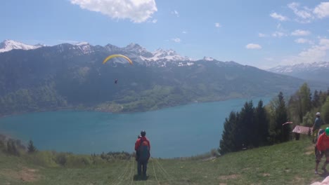 Un-Parapente-En-Vuelo-Sobre-El-Lago-Azul-Turquesa-En-Suiza