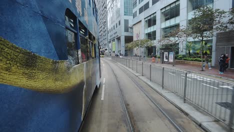 Double-Decker-Tram-Traveling-On-The-Road-And-Stops-On-The-Pedestrian-Crossing-With-People-Crossing-In-Hong-Kong---wide-rolling-shot
