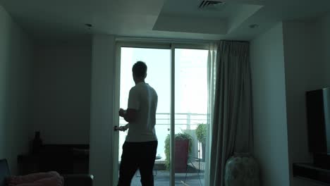 A-young-man-moves-to-the-balcony-with-a-cup-of-coffee