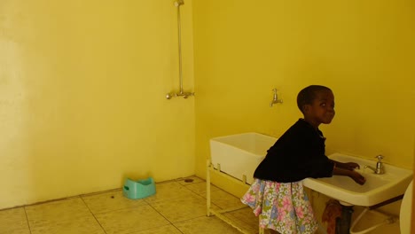 A-little-girl-with-disabilities-smiles-at-the-camera-while-drinking-water-in-the-school-restroom-in-this-heartwarming-clip