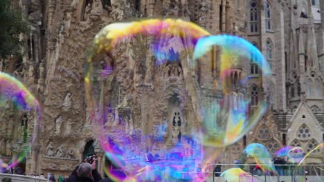 Tilting-UpShot,-Colorful-Bubbles-Flying-up,-People-taking-Picture-of-the-Sagrada-Familia-Church-in-the-background