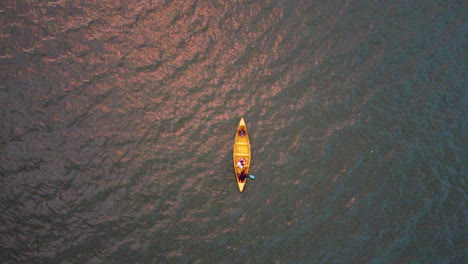 Friends-paddling-a-bright-yellow-canoe-across-lake-Ascending-aerial