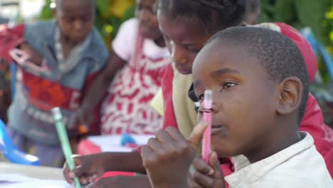 Junger-Afrikanischer-Junge-Hält-Crayola-Hoch,-Der-Farbstift-Und-Papier-Zeichnet