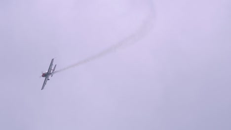 Blades-Aerobatic-Team-monoplane-aerobatic-flying-in-the-sky,-white-smoke-at-the-back