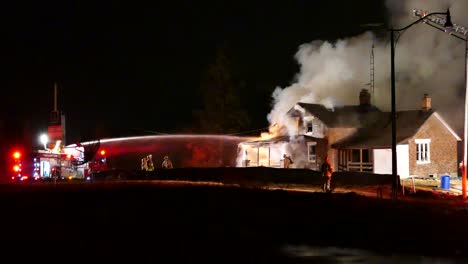 Multiple-Fire-Crews-Tackling-Large-House-Fire-At-Night-With-Smoke-Rising-From-Building