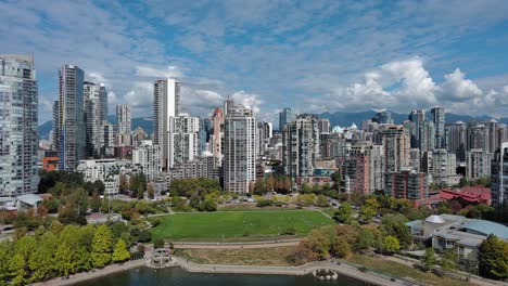 Drone-shot-of-David-Lam-park-and-downtown-Vancouver-in-the-summer-with-blue-sky,-kids-playing-in-the-park,-buildings-and-the-seawall