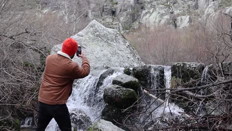 Man-Taking-a-Picture-of-a-Rocky-Creek-With-a-Smart-Phone-During-Winter