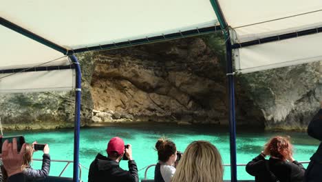 Turistas-En-Un-Barco-Observando-Y-Fotografiando-Las-Cuevas-Marinas-De-La-Isla-De-Comino.
