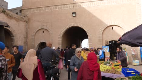 Women-talking-next-to-crowd-of-locals-passing-in-medina,-wide-shot