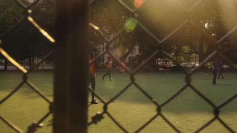 Slow-motion-shot-showing-soccer-player-playing-soccer-in-amateur-stadium-in-new-York---panning-view-behind-fence
