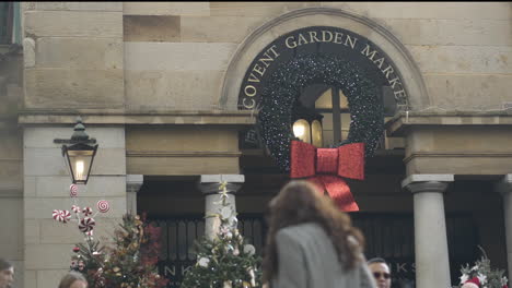 Pedestrians-walk-by-Covent-Garden-Market-decorated-with-Christmas-wreath-during-holiday-season