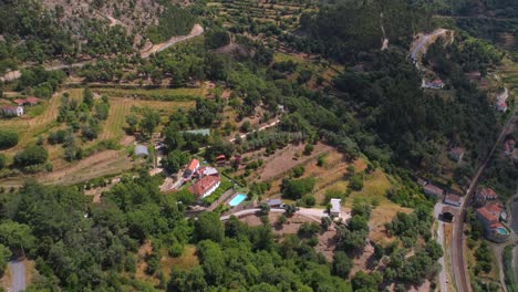 Douro-resort,-aerial,-drone-shot,-overlooking-a-hotel,-with-a-vineyard-,-a-pool-and-orange-fruit-garden,-at-the-Duero-river,-on-a-partly-sunny-day
