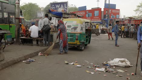 Woman-brushing-trash-of-street,-Delhi-India