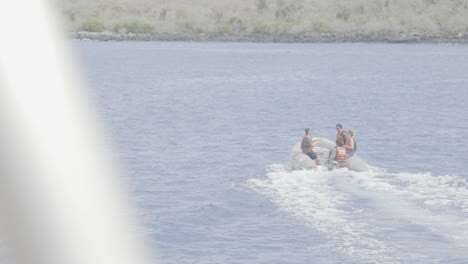 A-boat-or-panga-ride-with-4-people-onboard-is-heading-towards-an-island-with-green-vegetation-and-flora-in-the-Galapagos-islands