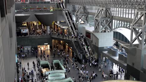 Looking-Down-At-Busy-Kyoto-Station-Central-Gate-with-people-going-up-and-down-on-escalator,-Japan