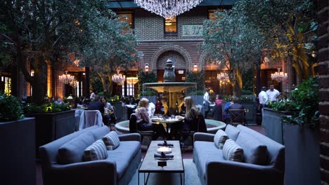 Zwei-Frauen-Sitzen-Im-Luxuriösen-Chicago-Restaurant,-Umgeben-Von-Bäumen-Und-Zeitgenössischer-Dekoration-Mit-Ausgefallenen-Kronleuchtern