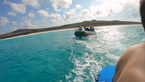 Von-Einem-Fahrenden-Boot-Aus-Sieht-Man-Ein-Anderes-Boot-Mit-Passagieren-An-Bord,-Das-Sich-Im-Türkisfarbenen-Und-Paradiesischen-Ozean-Der-Galapagos-Inseln-Vorwärts-Bewegt