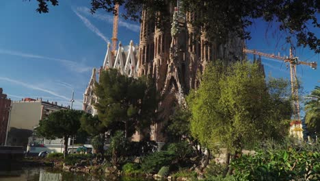 Moving-Forward-Shot,-Scenic-view-of-a-Pond-and-Trees-revealing-the-Sagrada-Familia-Church-in-Barcelona