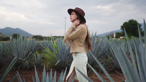 Weibliches-Model-Mit-Cowboyhut-Und-Sommerkleid-überquert-Agavenfelder-In-Mexiko-–-Mittlere-Kamerafahrt