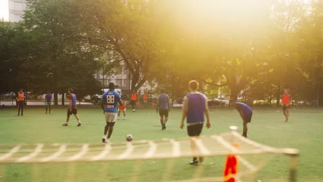 Schwenkaufnahme,-Die-Eine-Gruppe-Männlicher-Teenager-Zeigt,-Die-Bei-Sonnenuntergang-Auf-Einem-Amateurfeld-In-New-York-City-Fußball-Spielen