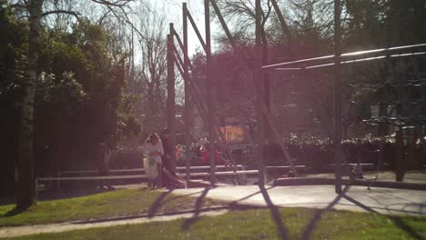 Family-In-At-Raspail-Park-With-Kids-On-Swing-Outside-In-The-Background
