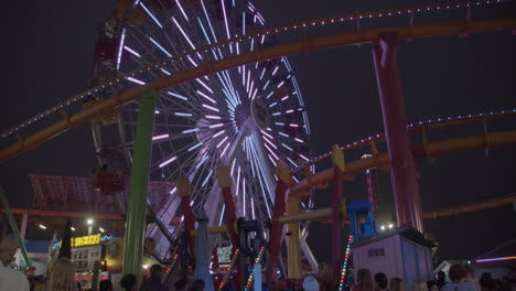 Cinematic-slow-motion-shot-of-Santa-Monica's-Pacific-Park-located-on-the-pier-with-famous-Ferris-Wheel-in-the-background