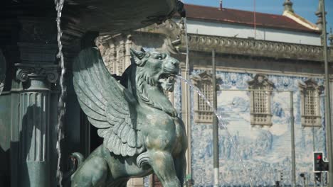 Medium-moving-shot,-Scenic-view-Ancient-Winged-Lion-Fountain-in-the-Town-Square-in-Porto,-Portugal,-Igreja-do-Carmo-church-in-the-background