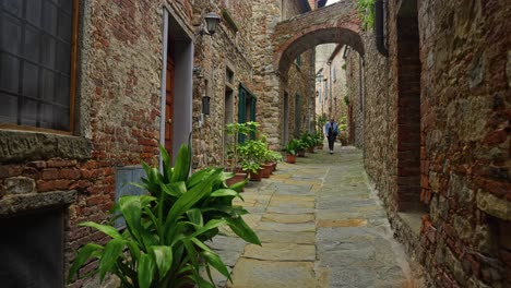 A-Female-Tourist-Walking-On-Typical-Narrow-Streets-Of-Lucignano,-Arezzo-Province,-Tuscany,-Italy