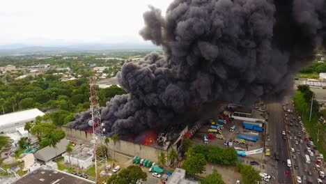 Aerial,-tracking,-drone-shot-of-firetrucks-and-firemen-extinguishing-a-building-fire,-cloudy-day,-in-Port-au-Prince,-Haiti