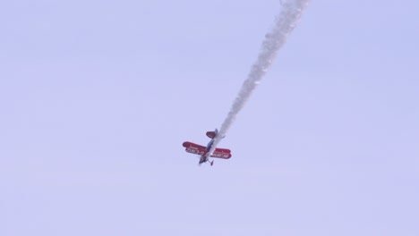 Aerobatic-flying-Muscle-biplane-nosedives-in-the-sky-in-slow-motion,-white-smoke-trails-from-tail