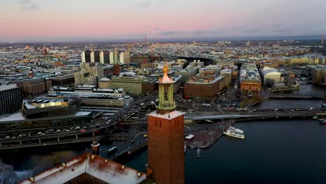 Reveal-drone-footage-of-the-Stockholm-City-Hall,-with-a-stunning-sunset-over-the-city's-skyline