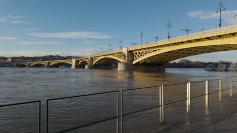 Slow-Motion-Tilt-Locked-Pedestal-shot-of-the-Flooded-Quay-and-Margaret-Bridge-in-Budapest,-Hungary-during-the-flood-of-River-Danube---December-26,-2023