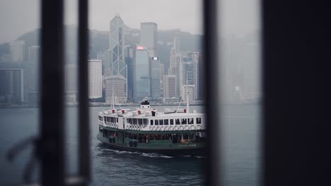 Star-Ferry-Boat-Segelt-Im-Hafen-Von-Victoria,-Vom-Fenster-Eines-Zimmers-In-Hongkong-Aus-Gesehen