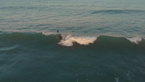 Surfer-riding-and-cruising-the-mini-mild-waves-of-beach-Santinho-at-golden-magic-hour