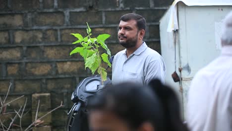 Indian-male-person-buying-a-plant-for-plantation,-follow-shot-of-plants-hanging-into-the-hand-on-the-market