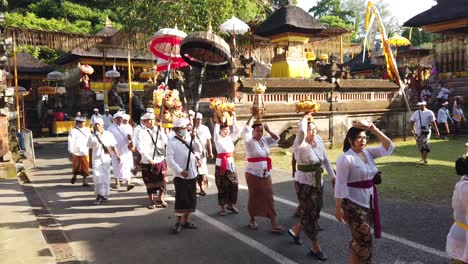 Balinese-People-Walk-in-Procession-Carry-Colorful-Umbrellas-and-Golden-Offerings-on-their-Heads,-Bali-Indonesia-Samuan-Tiga-Temple