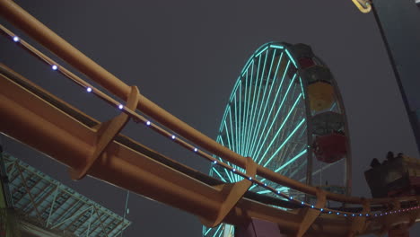 Rollercoaster-in-slow-motion-at-Pacific-Park-on-Santa-Monica-Pier-with-ferris-wheel-in-background