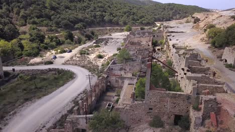 Drone-shot-flying-between-the-ruins-of-the-abandoned-coal-washery-and-an-empty-road,-in-Sardinia-Italy